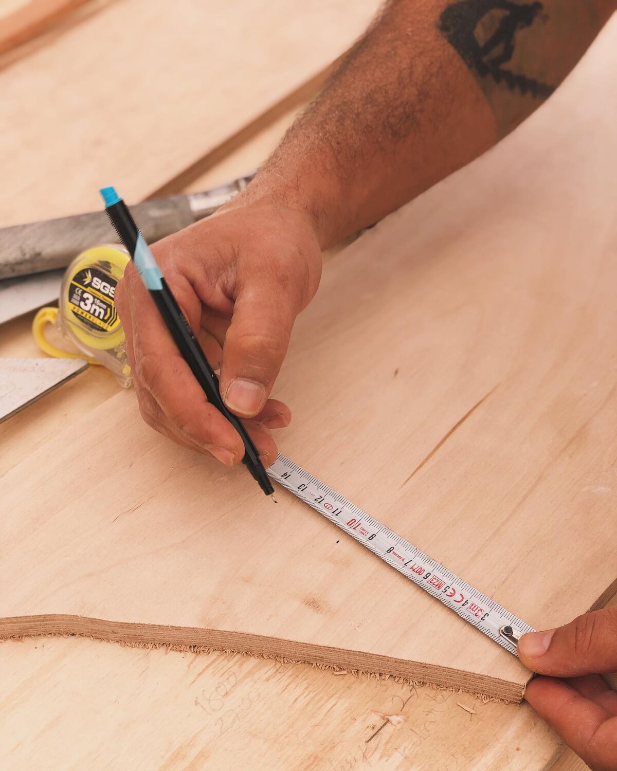 Marking out timber with pencil and tape measure in the Frida workshop
